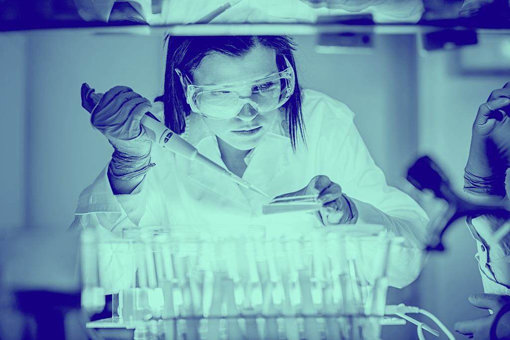 Blue washed image of female in lab distributing liquid into test tubes