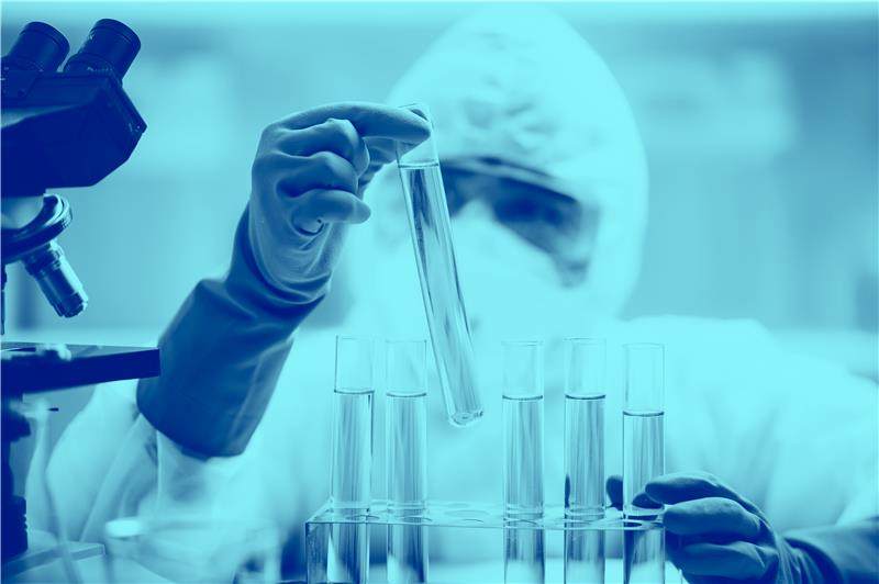 Blue washed image of scientist looking at test tube