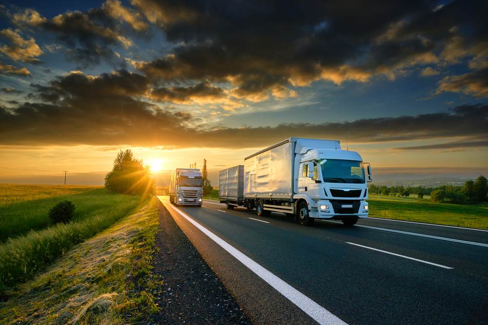 lorries on road with sun setting in background