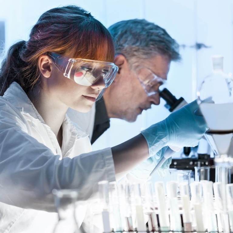 two scientists in lab looking into microscope