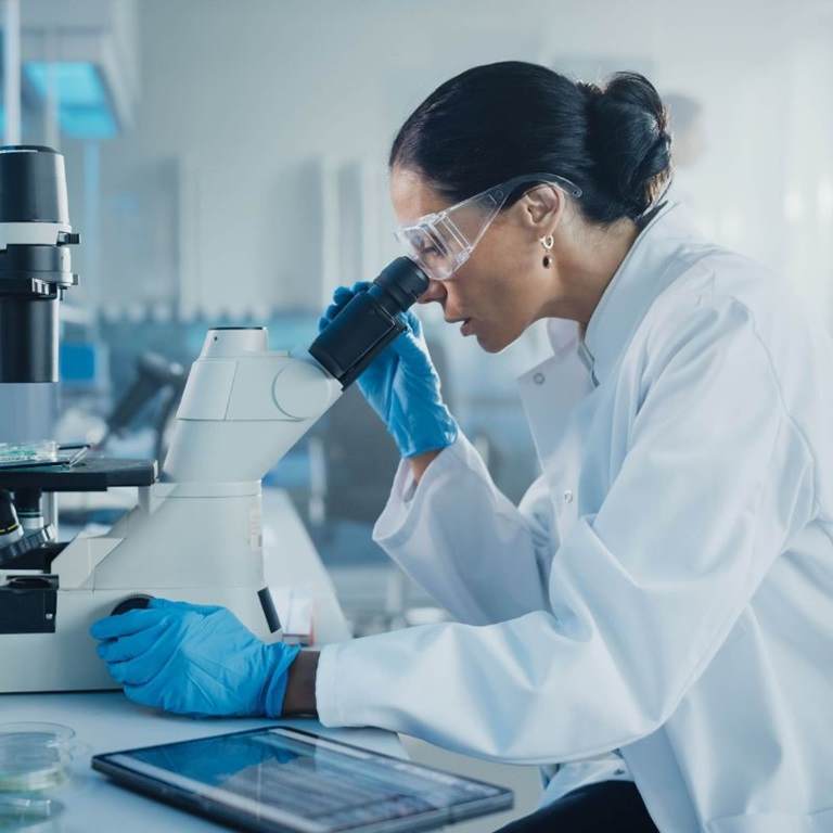 female in a lab looking through a telescope