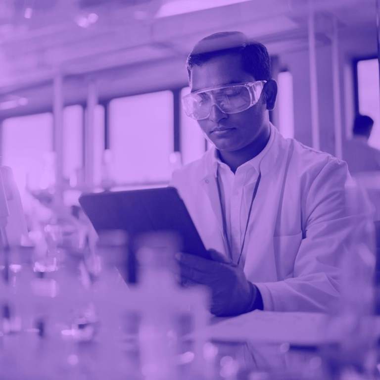 Purple washed image of scientist in lab wearing goggles