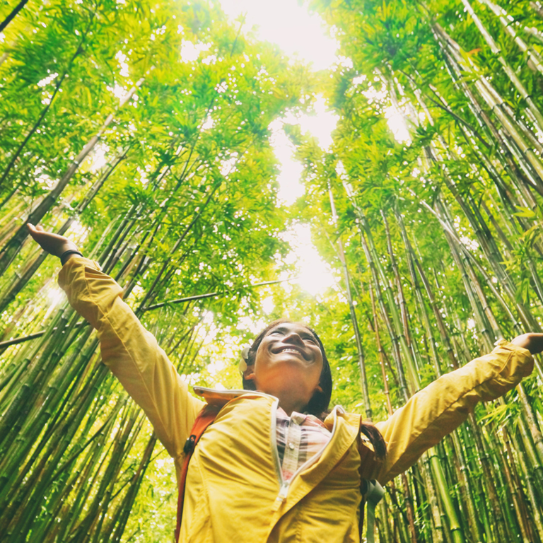 Woman in forest with arms in air