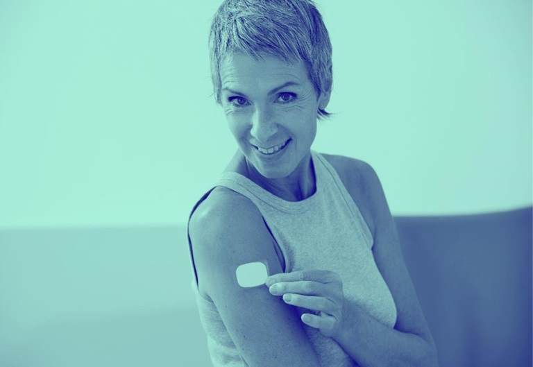 woman wearing transdermal patch on arm, smiling, with blue wash over image