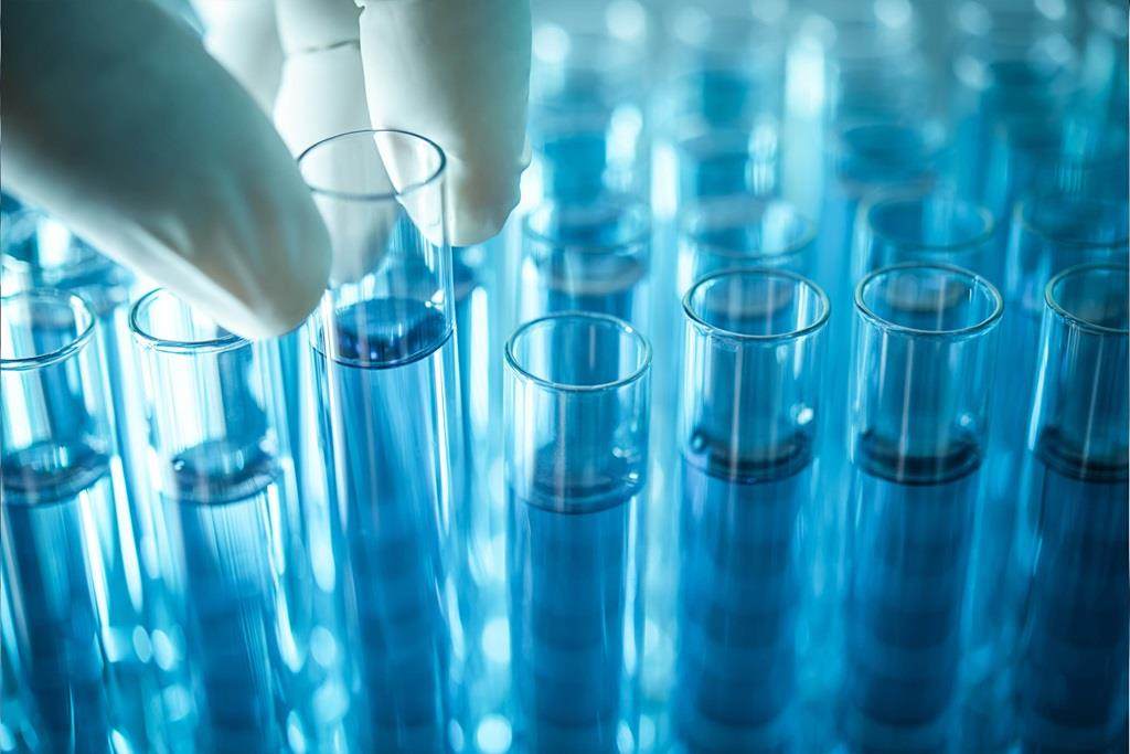 科学者の手がラックから試験管を拾う