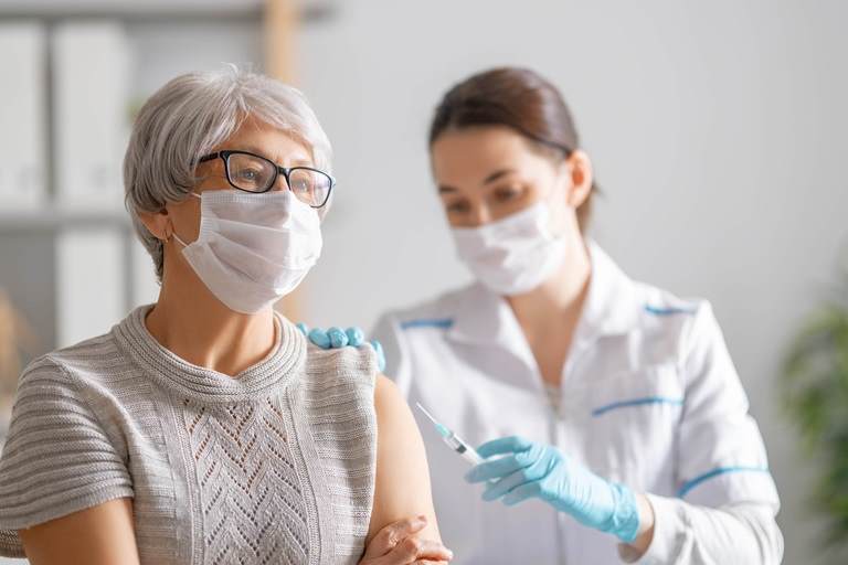 Doctor giving a senior woman a vaccination. 