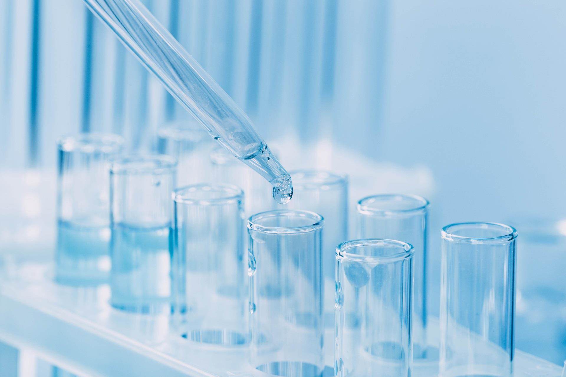 Vidraria de laboratório com um conta-gotas pingando líquido em um tubo de ensaio