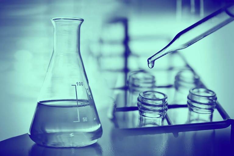 Flask in scientist hand with test tubes in laboratory