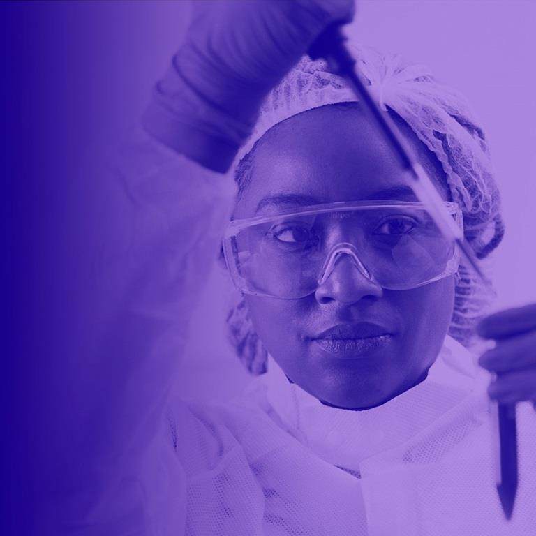 woman in lab dropping liquid into test tube with purple wash over image